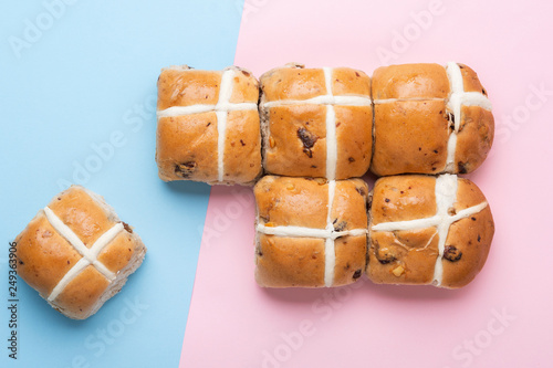 Six hot cross buns, traditional British Easter food on pink and blue background, top view, selective focus