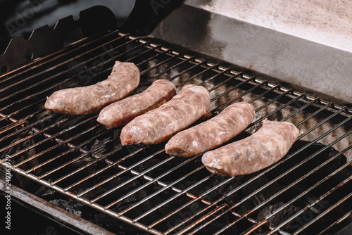 raw pork sausages cooking on barbecue grill grates