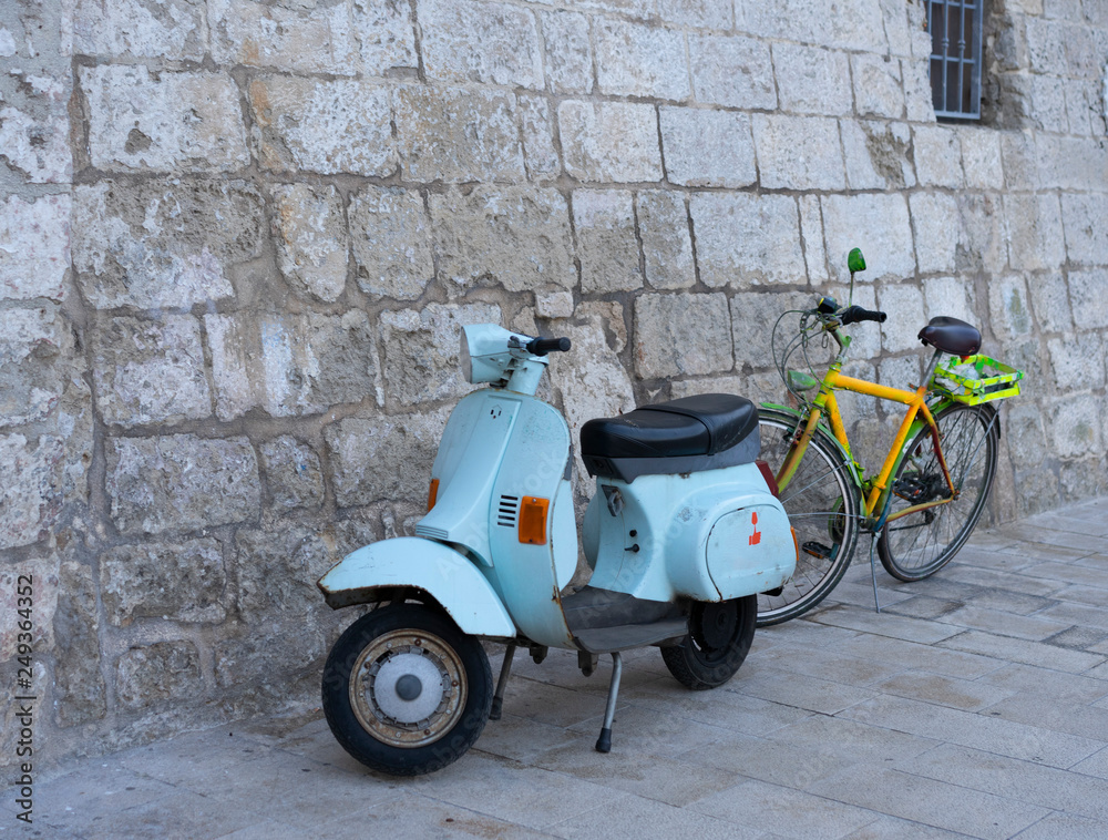 Old scooter and bike on the stone wall background