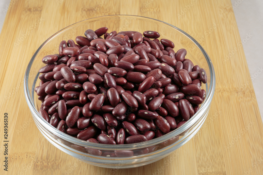 Dry red beans are in a glass bowl. Wooden background. Dry red beans are in a glass bowl. Wooden background.