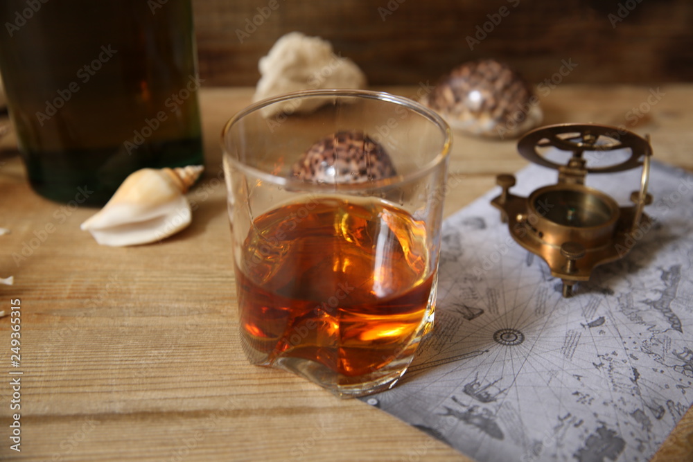glass of whiskey with a compass and shells on a wooden rustic table with copy space for text glass of whiskey with a compass and shells on a wooden rustic table with copy space for text