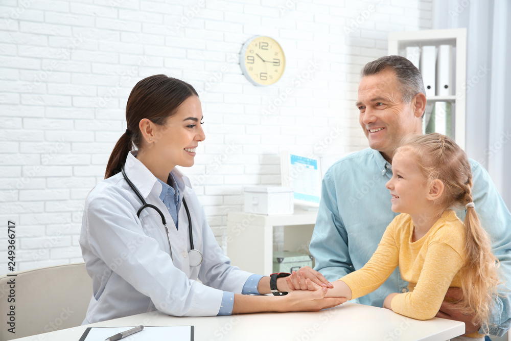 Mature man with granddaughter visiting doctor in hospital. Checking pulse Mature man with granddaughter visiting doctor in hospital. Checking pulse