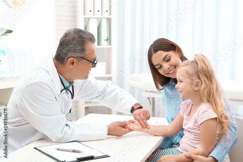 Young woman with daughter visiting doctor in hospital. Checking pulse