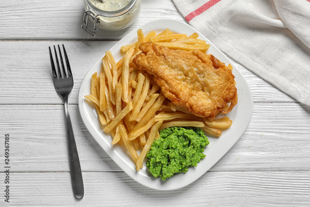 Plate with British traditional fish and potato chips on wooden background, top view Plate with British traditional fish and potato chips on wooden background, top view