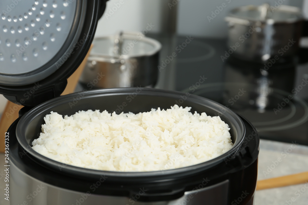 Modern cooker with fresh boiled rice in kitchen Modern cooker with fresh boiled rice in kitchen