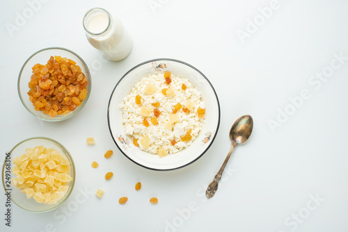 Cottage cheese with raisins and pineapple zucchini, with milk in a bowl on a white table. Diet, tasty and healthy food
