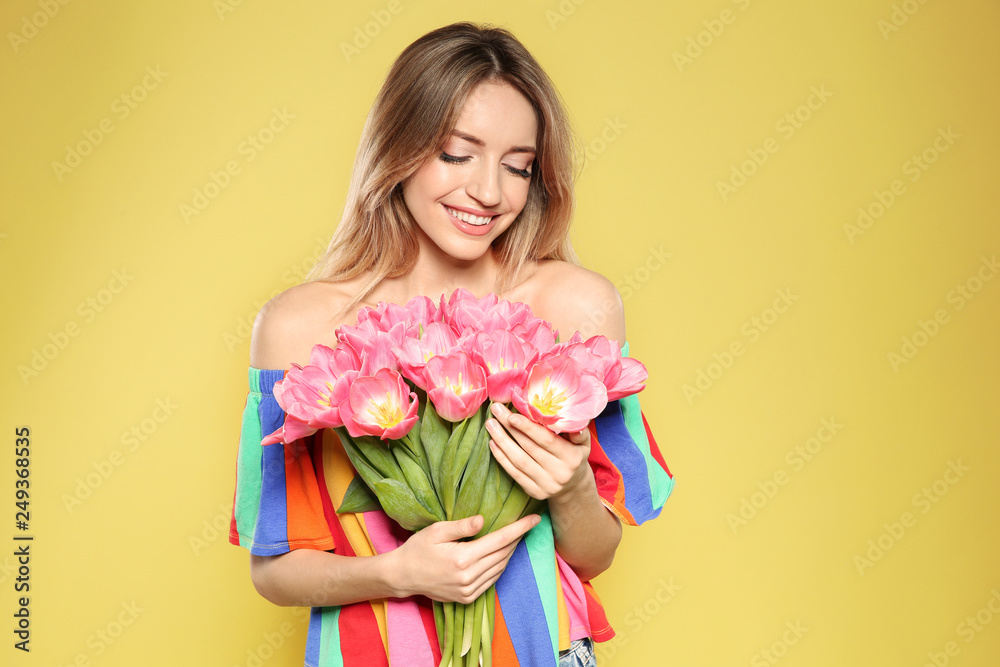Portrait of beautiful smiling girl with spring tulips on yellow background. International Women's Day Portrait of beautiful smiling girl with spring tulips on yellow background. International Women's Day