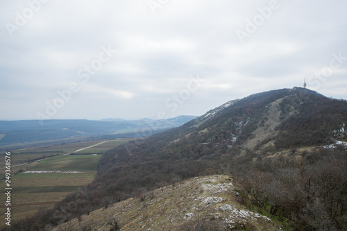 View from the highest point of the deserted edge to the edge of the rocks and boots moving down into the abyss