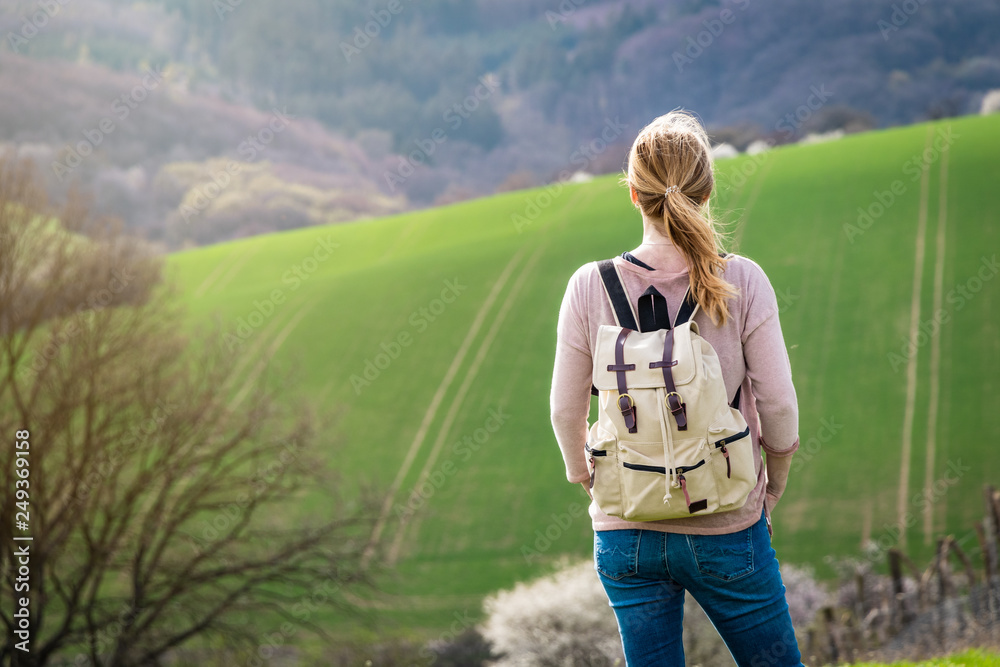 Woman hiker standing in rural scenery at springtime, travel concept