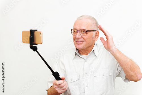 Old active man taking selfie with mobile phone isolated on grey background photo