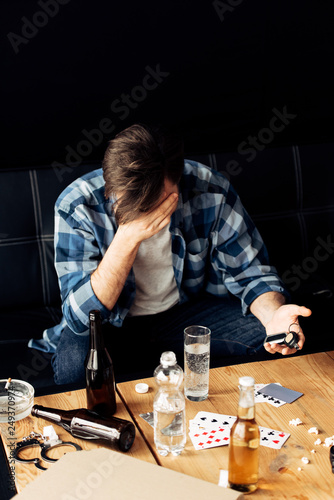 man covering face and feeling embarrassed while holding car key after party