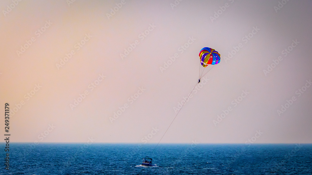 Parasailing on Baga Beach, Goa in summer. person under parachute hanging mid air. Having fun. Tropical Paradise. Positive human emotions, feelings, family, travel, vacation. Parasailing on Baga Beach, Goa in summer. person under parachute hanging mid air. Having fun. Tropical Paradise. Positive human emotions, feelings, family, travel, vacation.