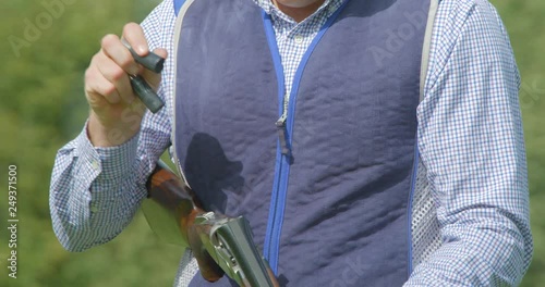 A clay Pigeon shooter breaks the barrels of his double barrelled shotgun and the cartridges fly out in slow motion. photo