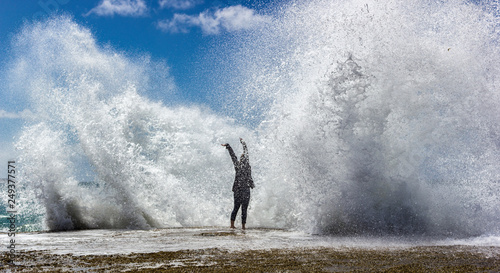 Fototapeta Naklejka Na Ścianę i Meble -  yung woman enjoying the moment when huge Powerful Waves crashing on rocks
