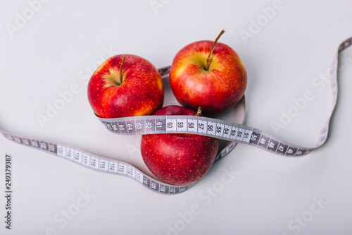 Red apple wrapped centimeter lies on a white table. Apple diet