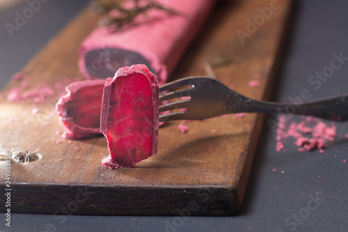 basturma slices. Bastirma in a pink crust of flour and spices on a dark background photo