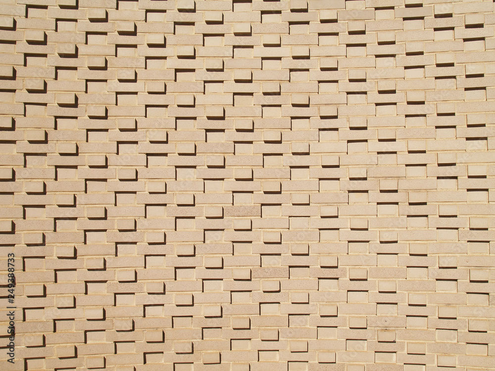 A light colored, beige multi-layered and multi-sized brick wall. A light colored, beige multi-layered and multi-sized brick wall.