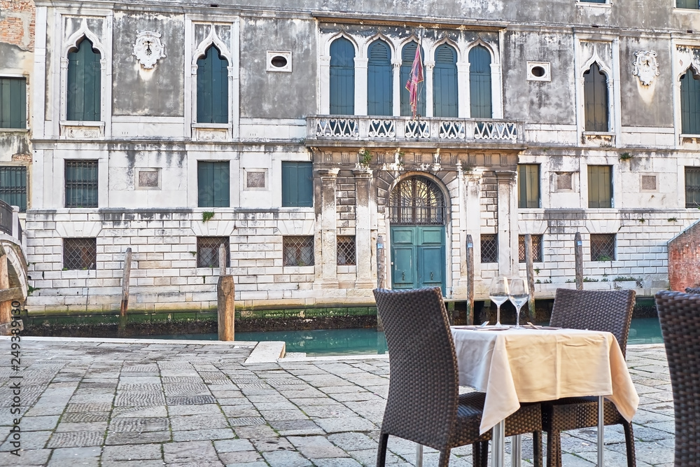 Naklejka premium Restaurant table near the canal in Venice, Italy.