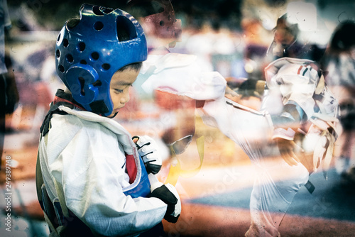 Taekwondo Asian kid with head guard. Double exposure another player during the tournament taekwondo kids in stadiums. Add old film filter and dust for feeling of former athlete history. © kokliang1981
