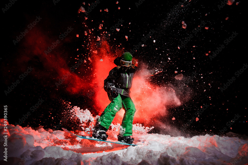 Fototapeta Active female snowboarder dressed in a green sportswear jumping on the snow