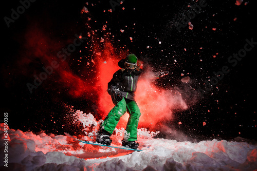 Active female snowboarder dressed in a green sportswear jumping on the snow