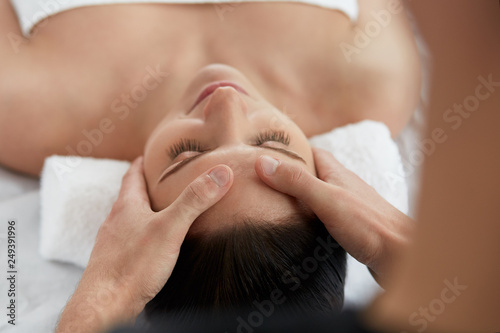 Young beautiful woman enjoying anti-aging facial massage.Male therapist making head massage to female client.Professional masseur.Relaxation,beauty,spa,body and face treatment concept.