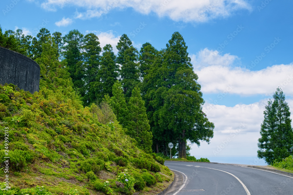 A road across mountains, covered by greenery on Sao Miguel island of Azores, Portugal.