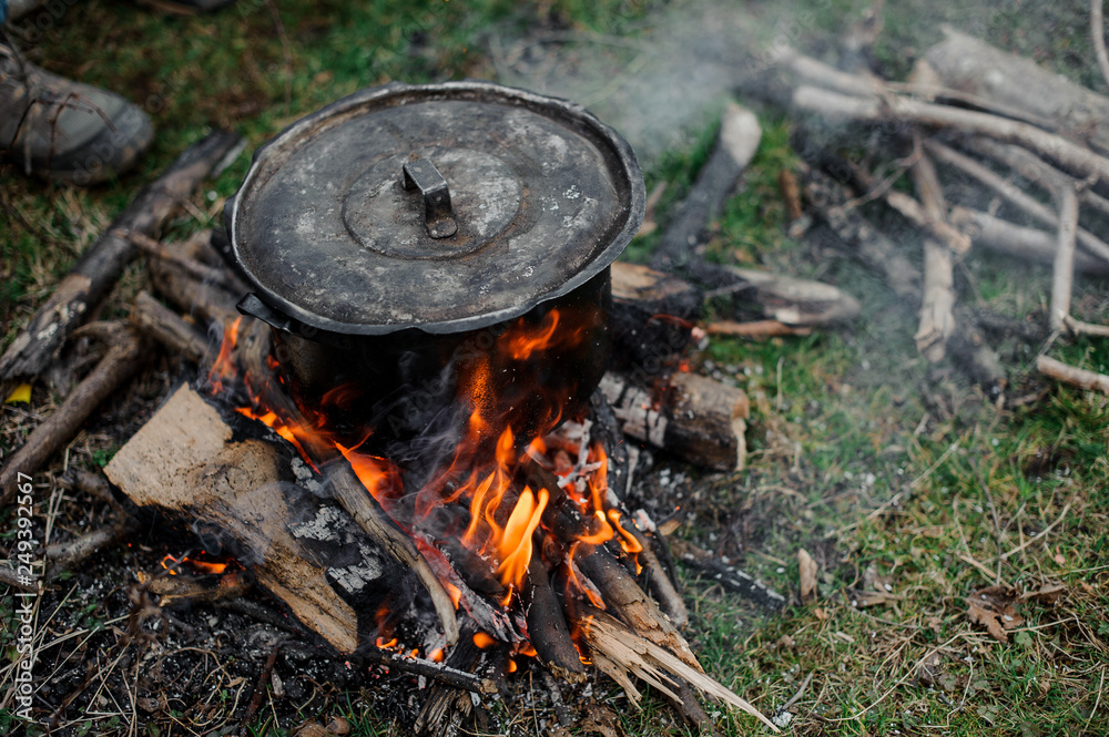 Black pan with a cover standing on the bonfire in the forest Black pan with a cover standing on the bonfire in the forest