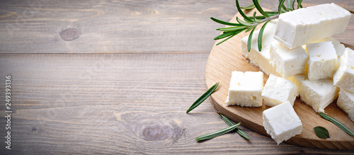 Feta cheese with rosemary on wood background. Top view with space for text