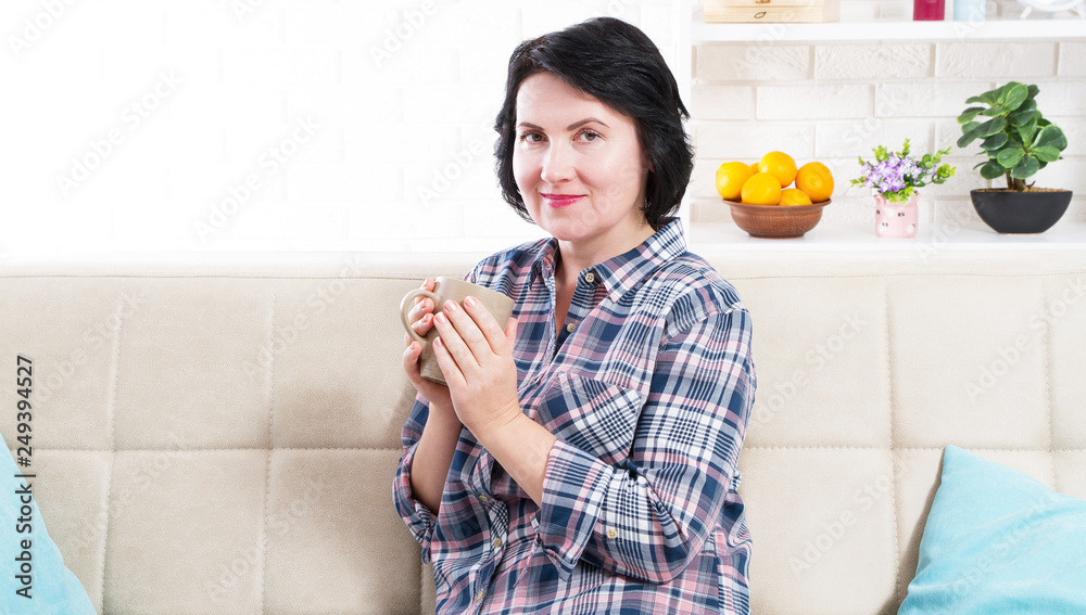 beautiful young woman holding mug with hot beverage on sofa at home beautiful young woman holding mug with hot beverage on sofa at home