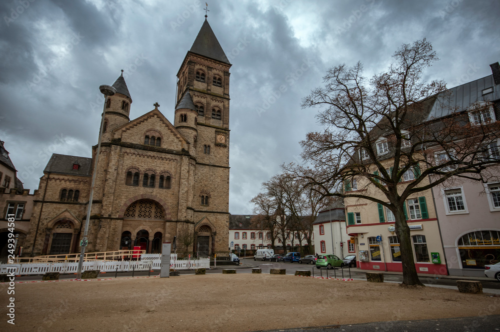 Trier / Germany - February 9 / 2019 : front view of St Paulus church at a cloudy day and a tree at side of it