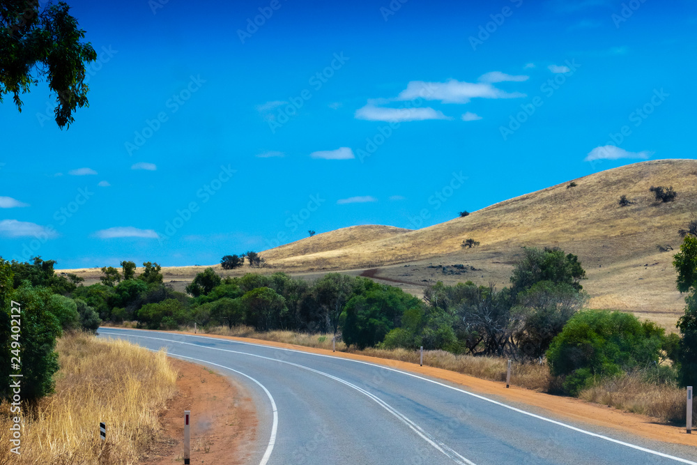 Curvy road leading through the dry hills of Western Australia