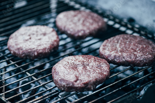 uncooked fresh burger cutlets grilling on bbq grid