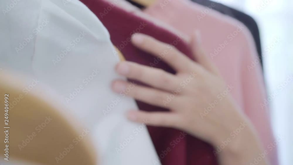 Beautiful attractive young Asian woman choosing her fashion outfit clothes in closet at home or store. Girl think what to wear sweater. Home wardrobe or clothing shop changing room. Beautiful attractive young Asian woman choosing her fashion outfit clothes in closet at home or store. Girl think what to wear sweater. Home wardrobe or clothing shop changing room.