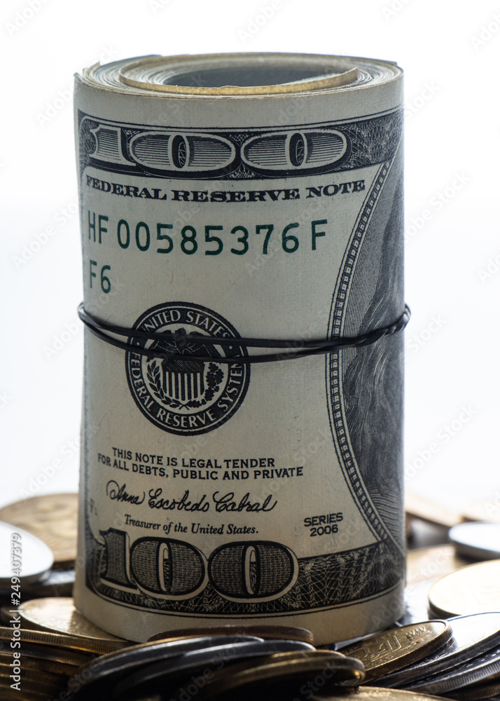 100 dollar bills twisted into tube and tied with an elastic band. white background.