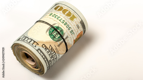 100 dollar bills twisted into tube and tied with an elastic band. white background.