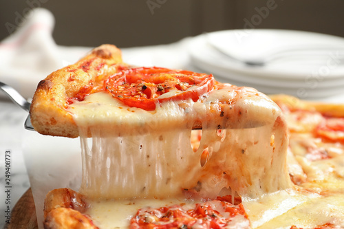 Taking slice of hot cheese pizza Margherita on table, closeup