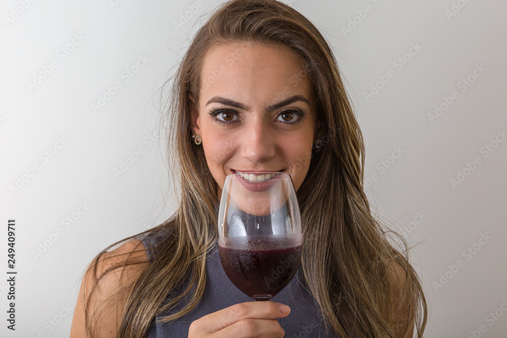 Smiling young woman sommelier with red wine in glass over white background Smiling young woman sommelier with red wine in glass over white background