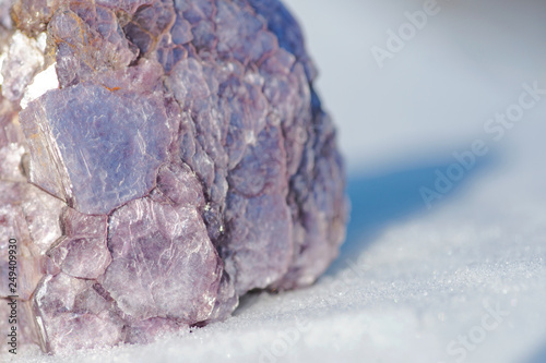 фотографія Rough Purple Lepidolite cluster from Brazil on white snow at a sunny winter day