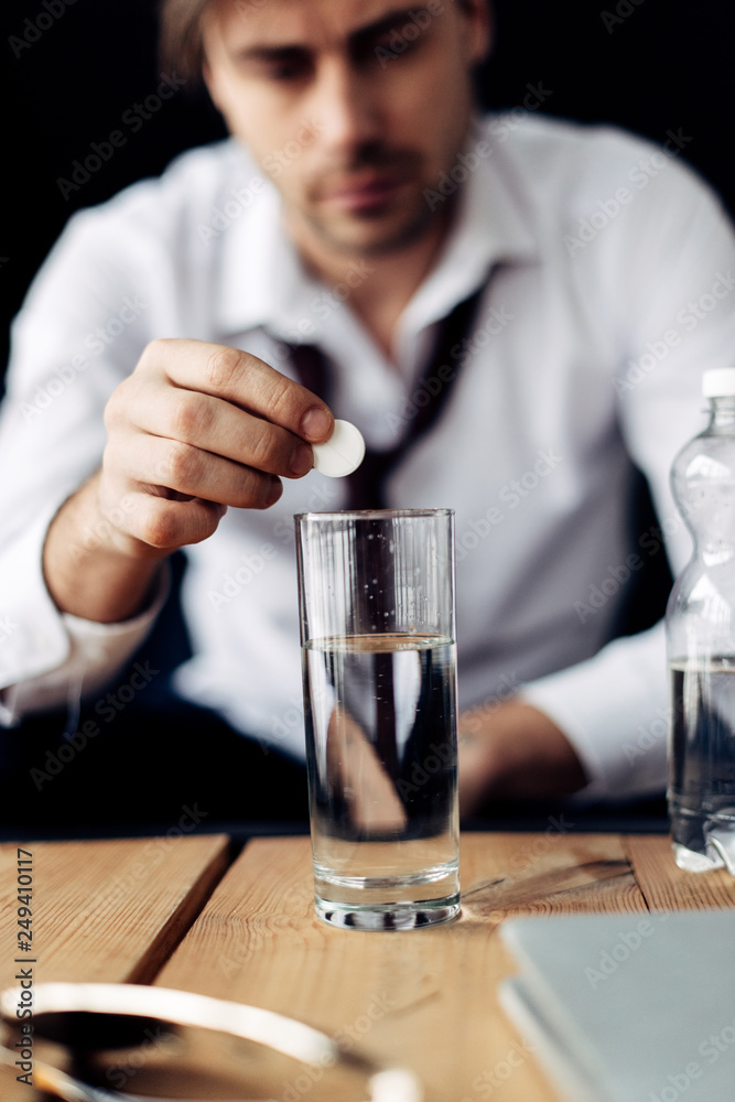 selective focus of man putting aspirin in glass of water