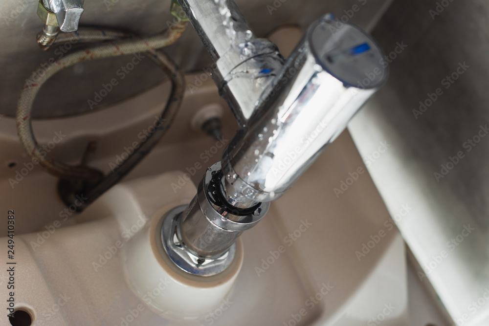 Leaking steel pipes under sink with water drops Leaking steel pipes under sink with water drops