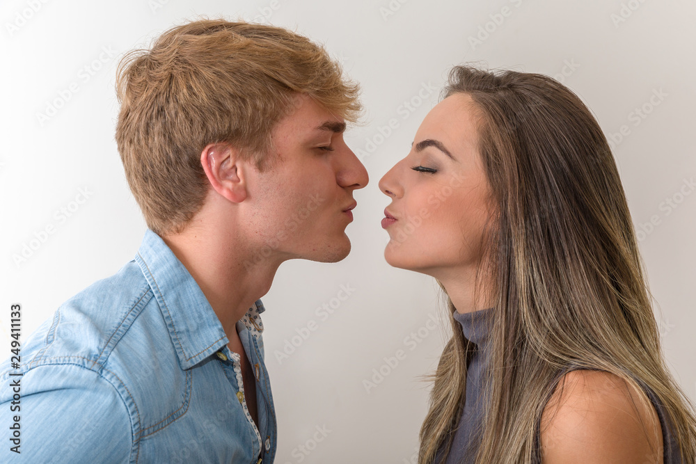 Side view of happy couple going to kiss on white background
