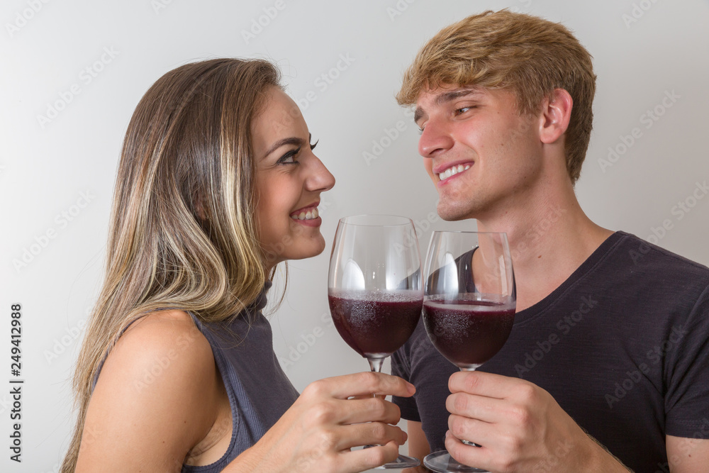 Joyful young couple making a toast with glasses of wine isolated on white background Joyful young couple making a toast with glasses of wine isolated on white background