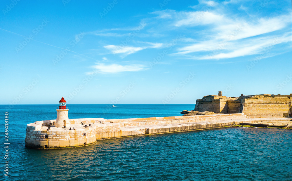 Red Lighthouse in Grand Harbour in Valletta city. Fort Ricasoli. Malta country. Mediterranean sea. Morning time and blue sky and clouds