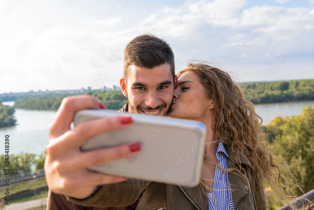 Happy young couple taking selfie photos near the river