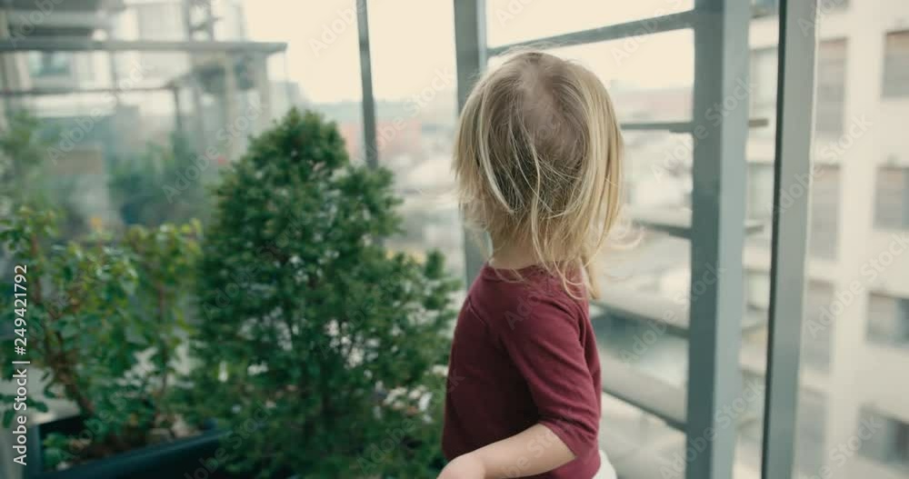 Little toddler playing on the balcony of high ris ein the city Little toddler playing on the balcony of high ris ein the city