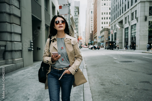Photography girl traveler in sunglasses walking on street in busy business area with skyscraper building surrounding