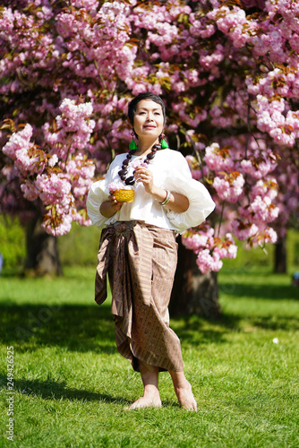 Femme debout en habit traditionnel devant des sakuras en fleurs