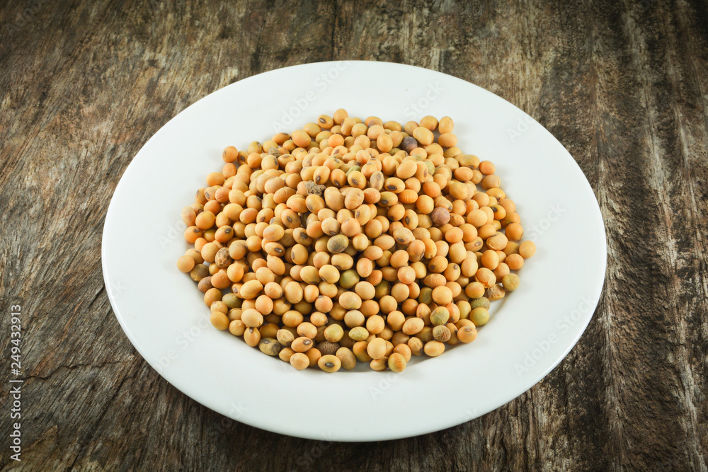 soybeans or soya beans grain seed on white plate on rustic wood background soybeans or soya beans grain seed on white plate on rustic wood background