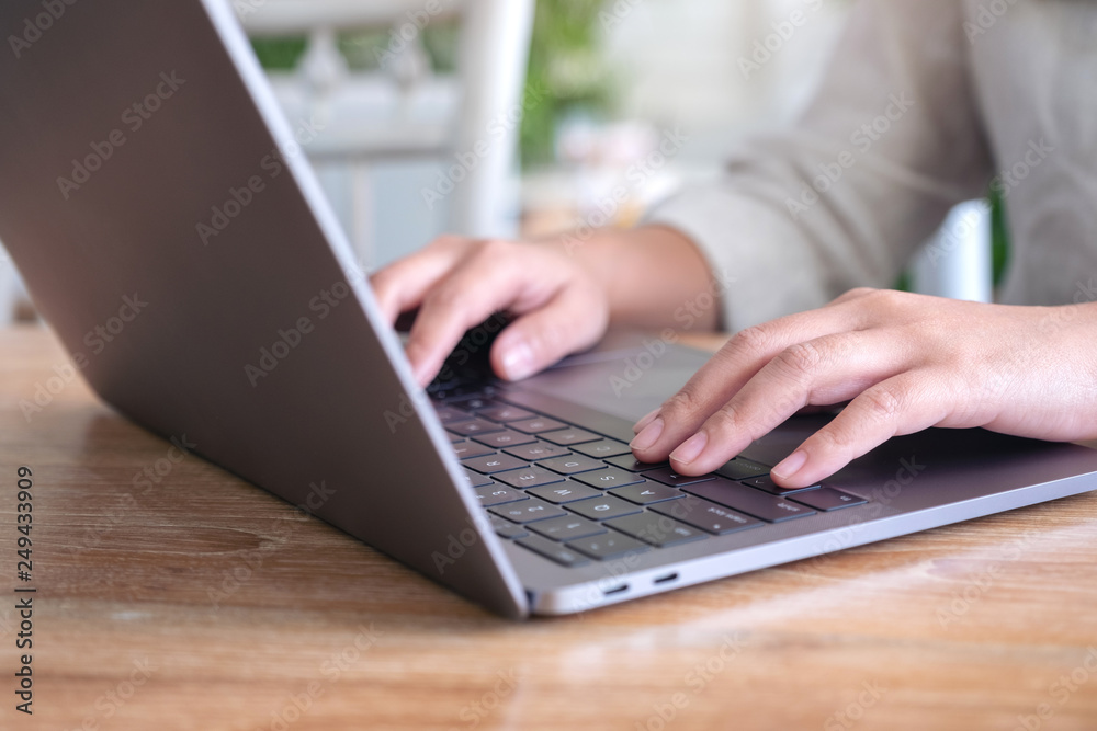 Closeup image of woman's hands using and typing on laptop keyboard on the table